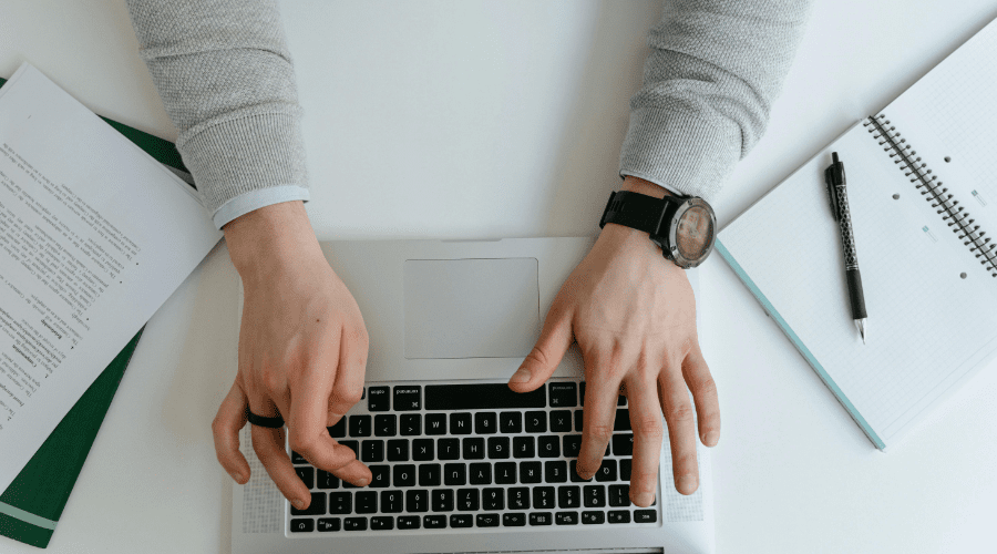 manos escribiendo en un macbook